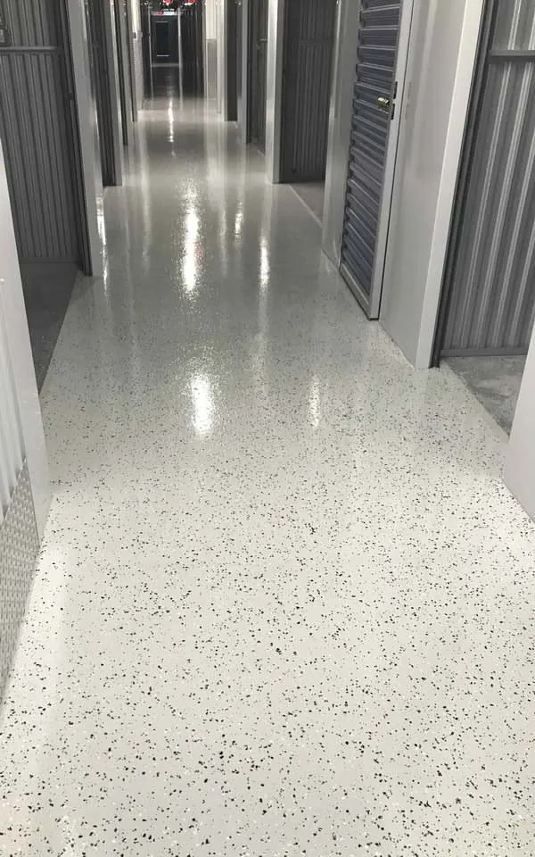 Pasillo de bodegas con piso epóxico flake blanco con hojuelas negras